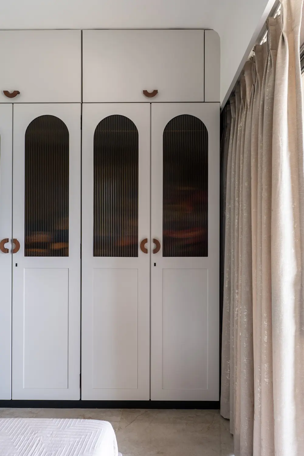 Tall white wardrobe with arched ribbed-glass doors