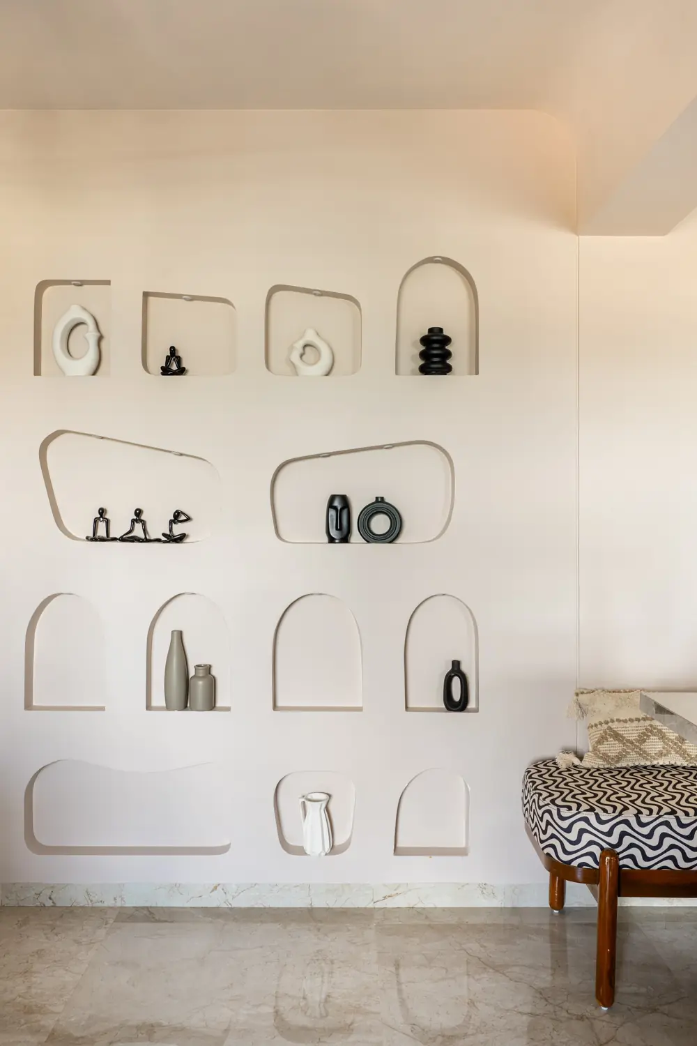 White wall of arched display niches holding black ceramics