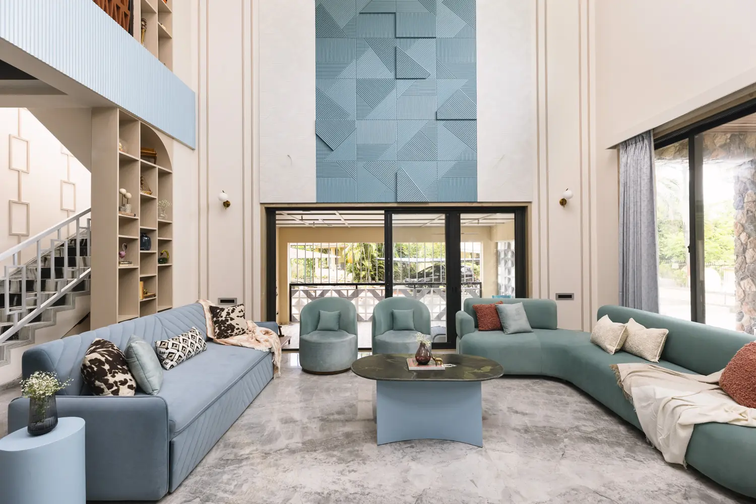 Double-height living room with a powder-blue geometric relief wall