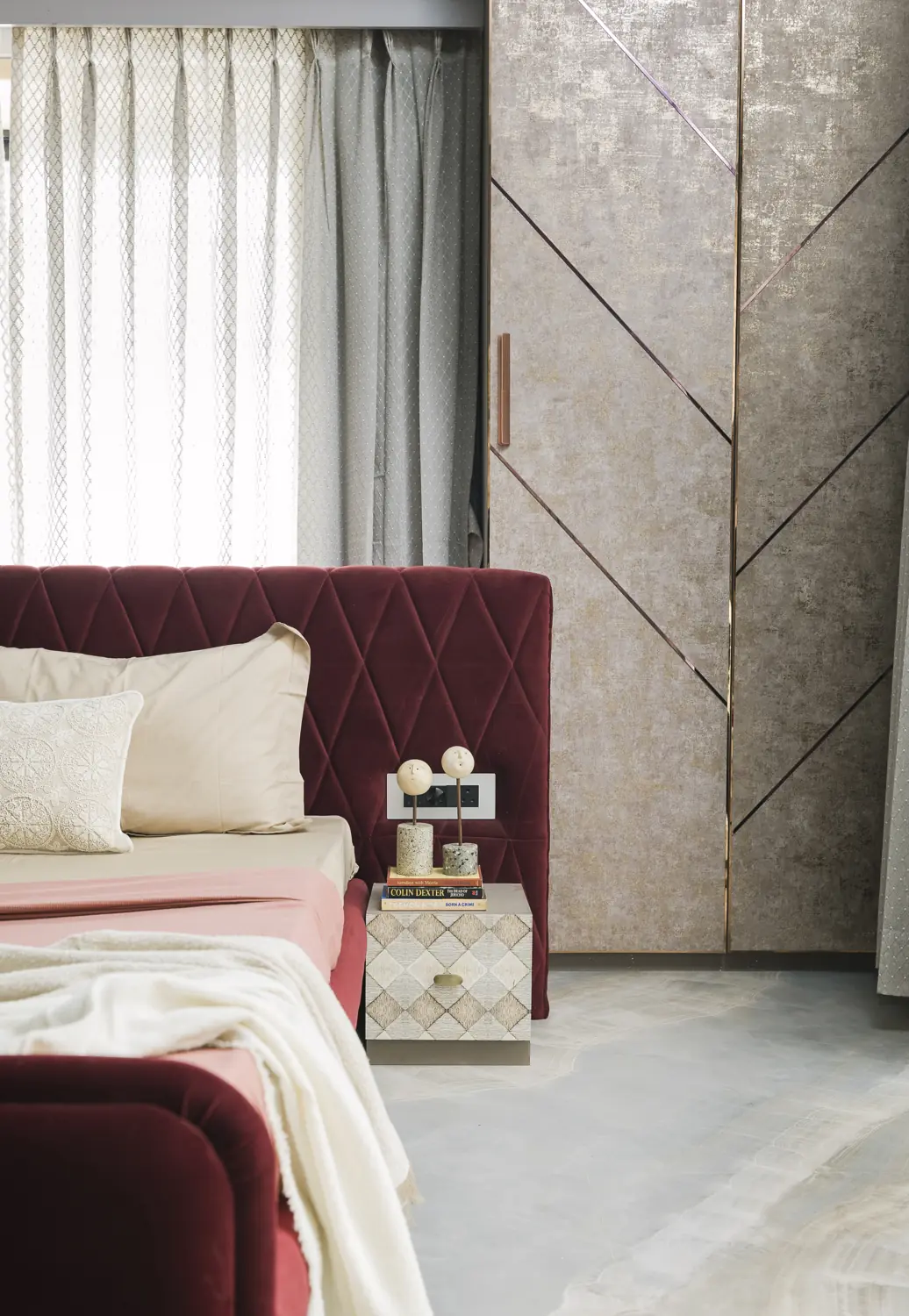 Plum bed and bedside table in soft window light