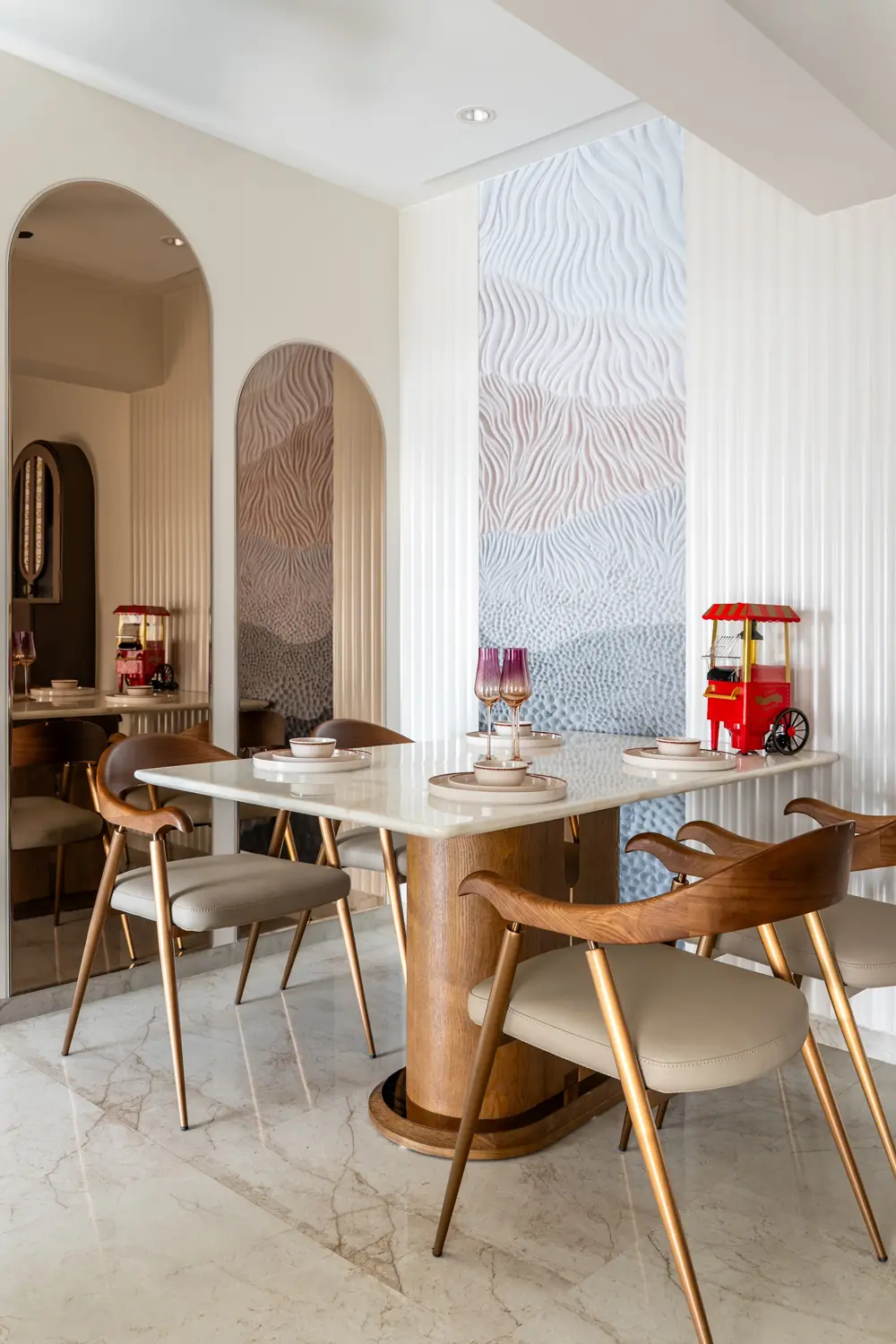Dining area with a round table, curved chairs and a carved wall