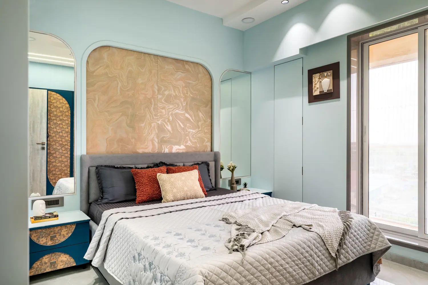 Powder-blue bedroom with a navy headboard under a gold textured arch