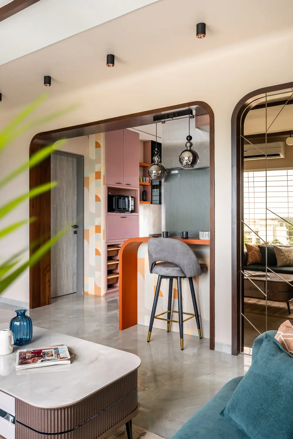 Blush-pink kitchen with a terrazzo breakfast counter under a wooden arch