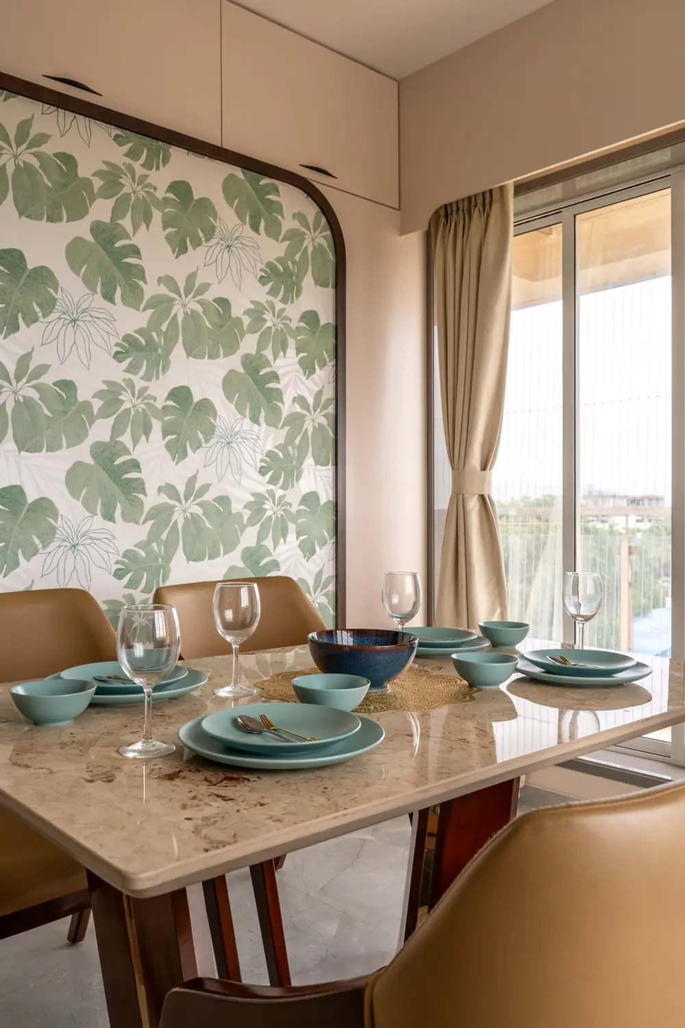 Dining table set against a leaf-print wall